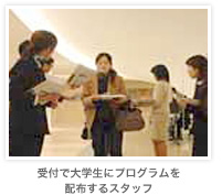 受付で大学生にプログラムを配布するスタッフ